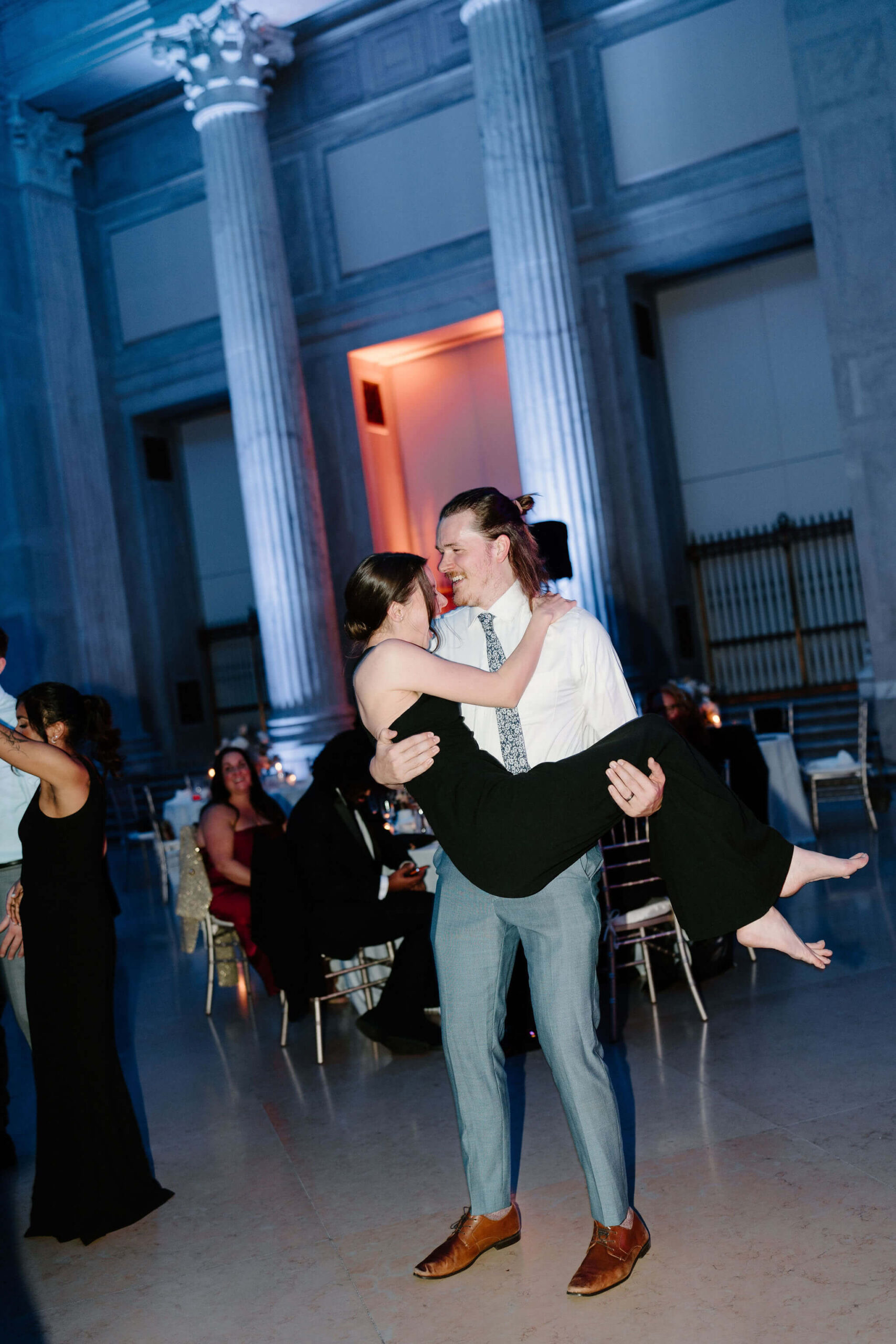 two guests dancing and smiling at a wedding reception, one lifting the other and spinning her