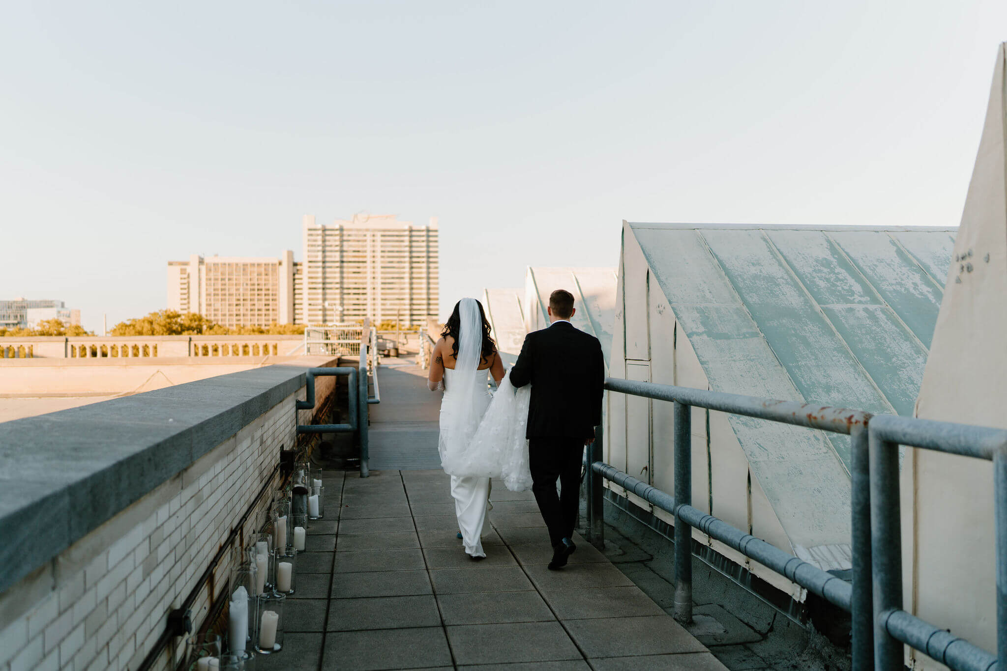 groom holding bride's train as they walk up to the roof of the franklin institute