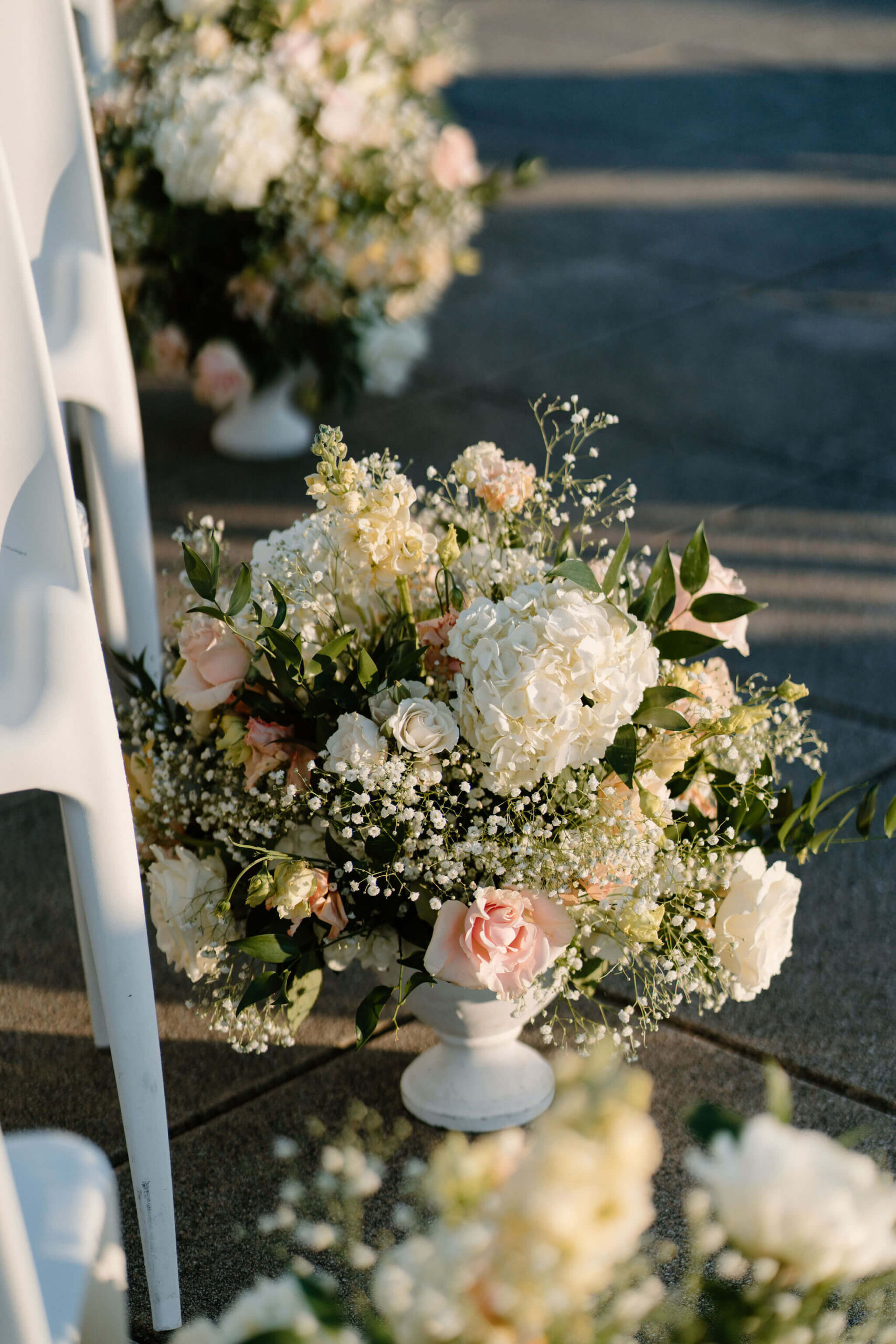 close up of a bursting floral arrangement with hydrangeas, roses, baby's breath, and olive branches