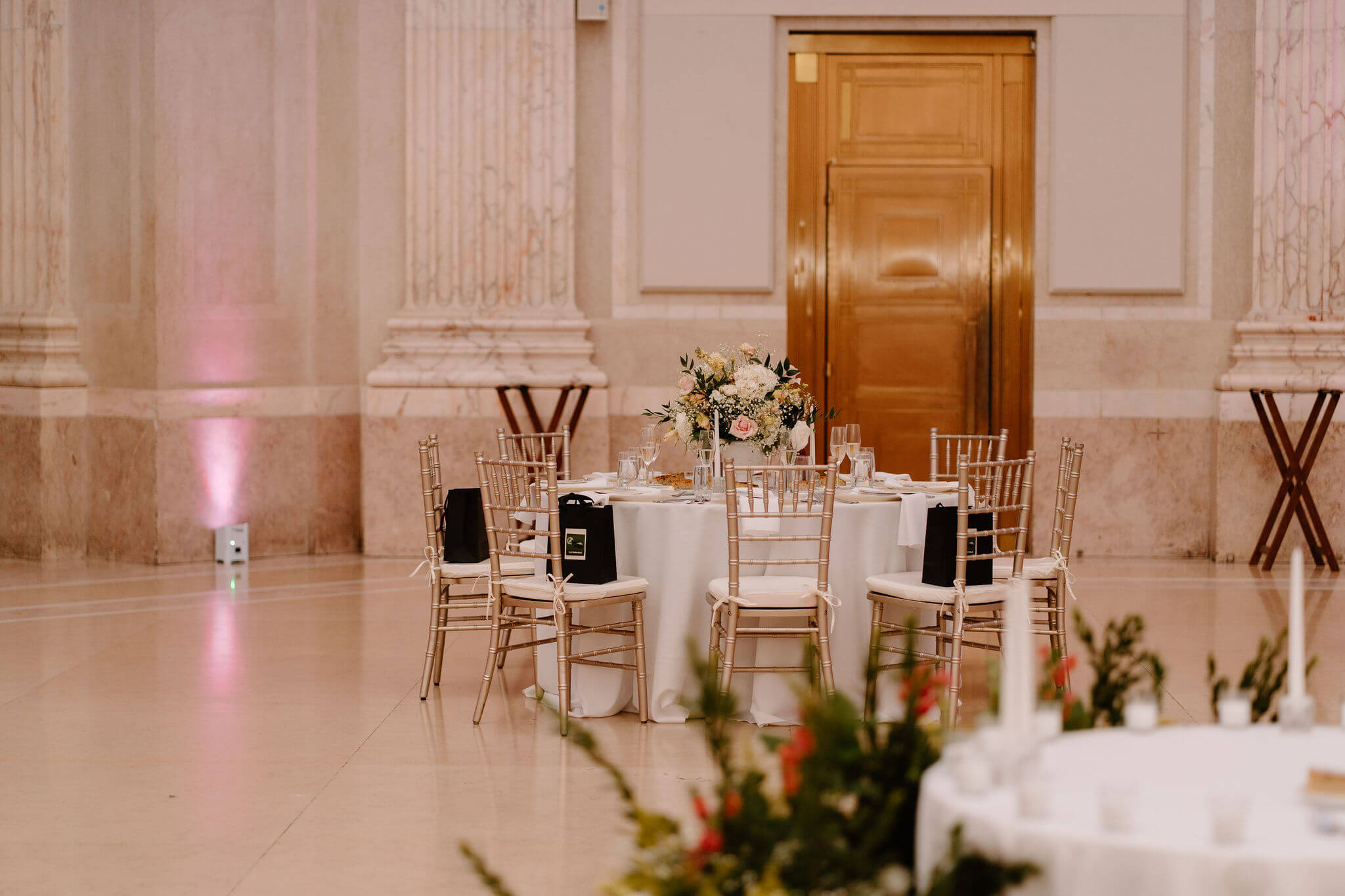 a franklin institute wedding reception table, decorated with white linens and a large pink-and-white floral arrangement