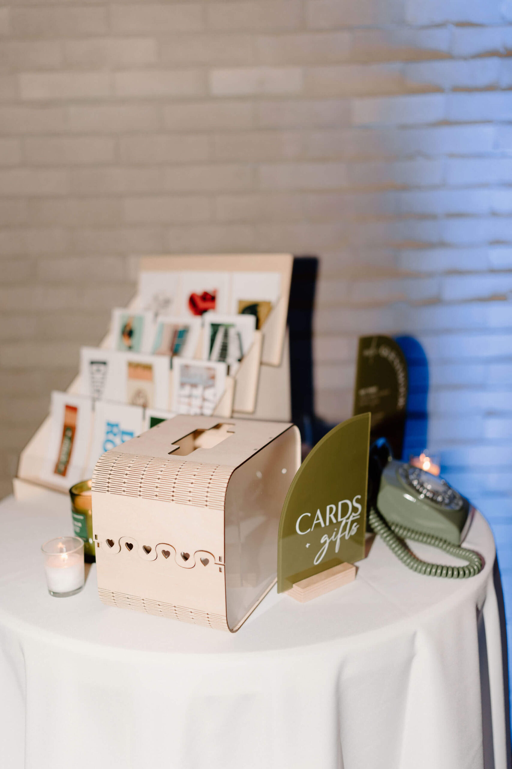 green sign that reads "cards & gifts", next to a wooden card box, a postcard stand, and a green rotary phone for an audio guestbook