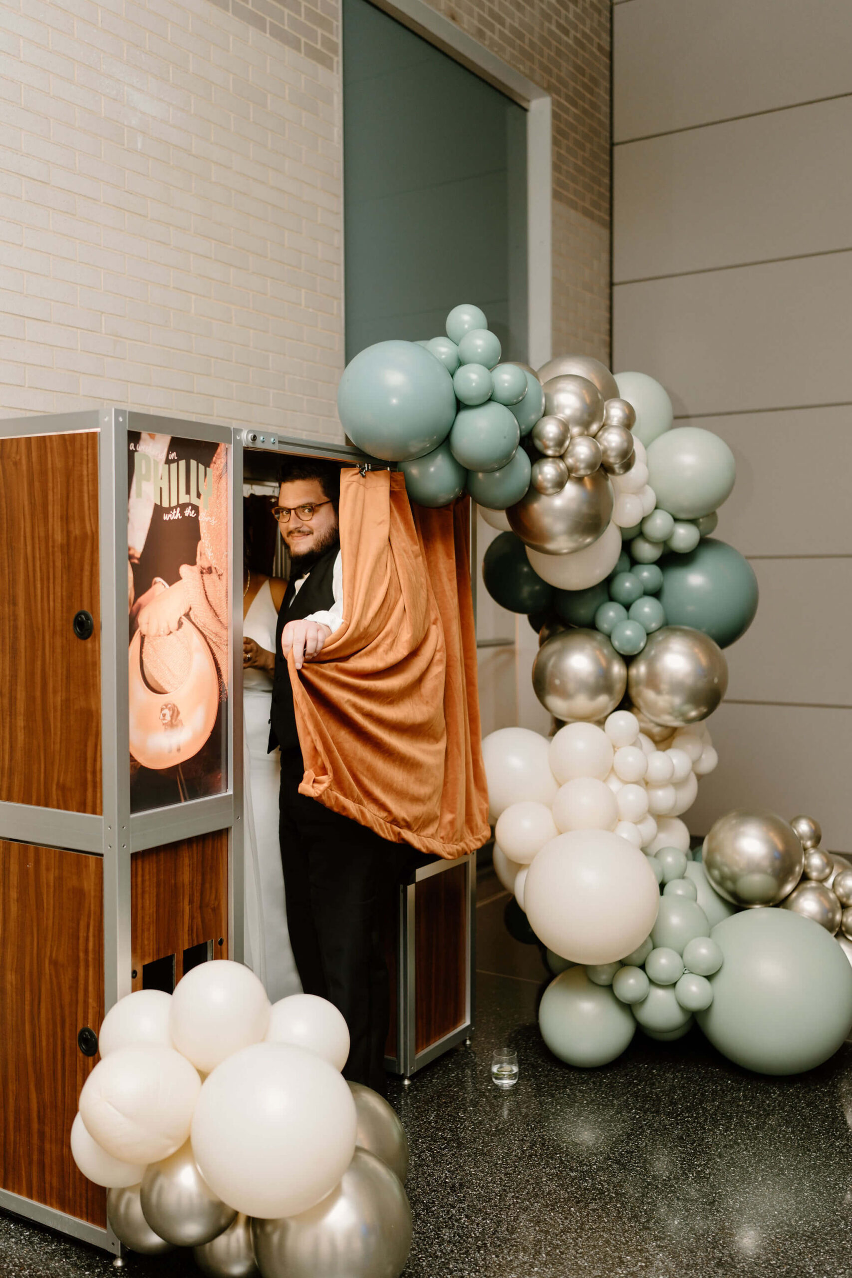 a guest smiling at the camera as he steps into the photobooth during the wedding reception