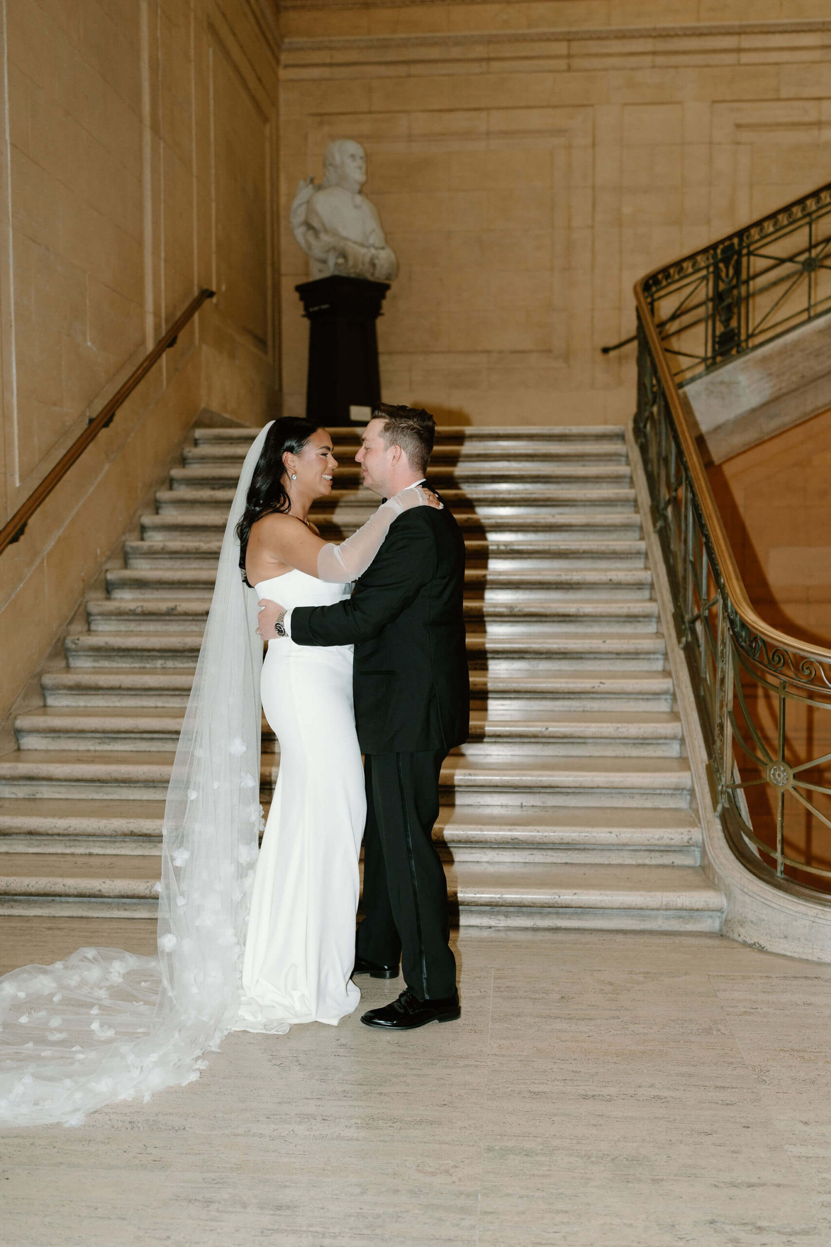 bride and groom kissing on large marble staircase, while bride's cathedral-length veil flows down the stairs behind her at their franklin institute wedding