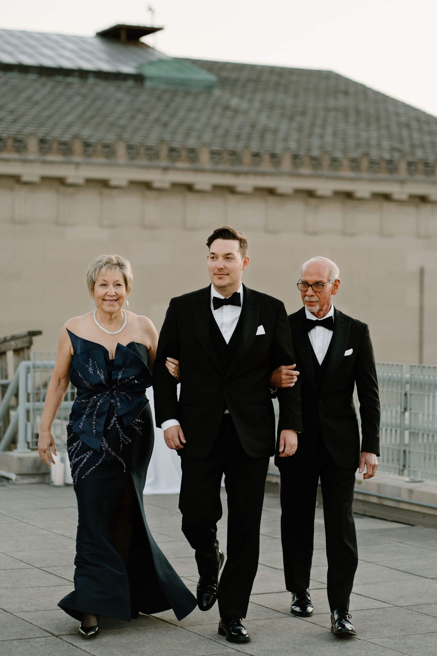 Groom being walked down the aisle at his wedding ceremony by his mother and father