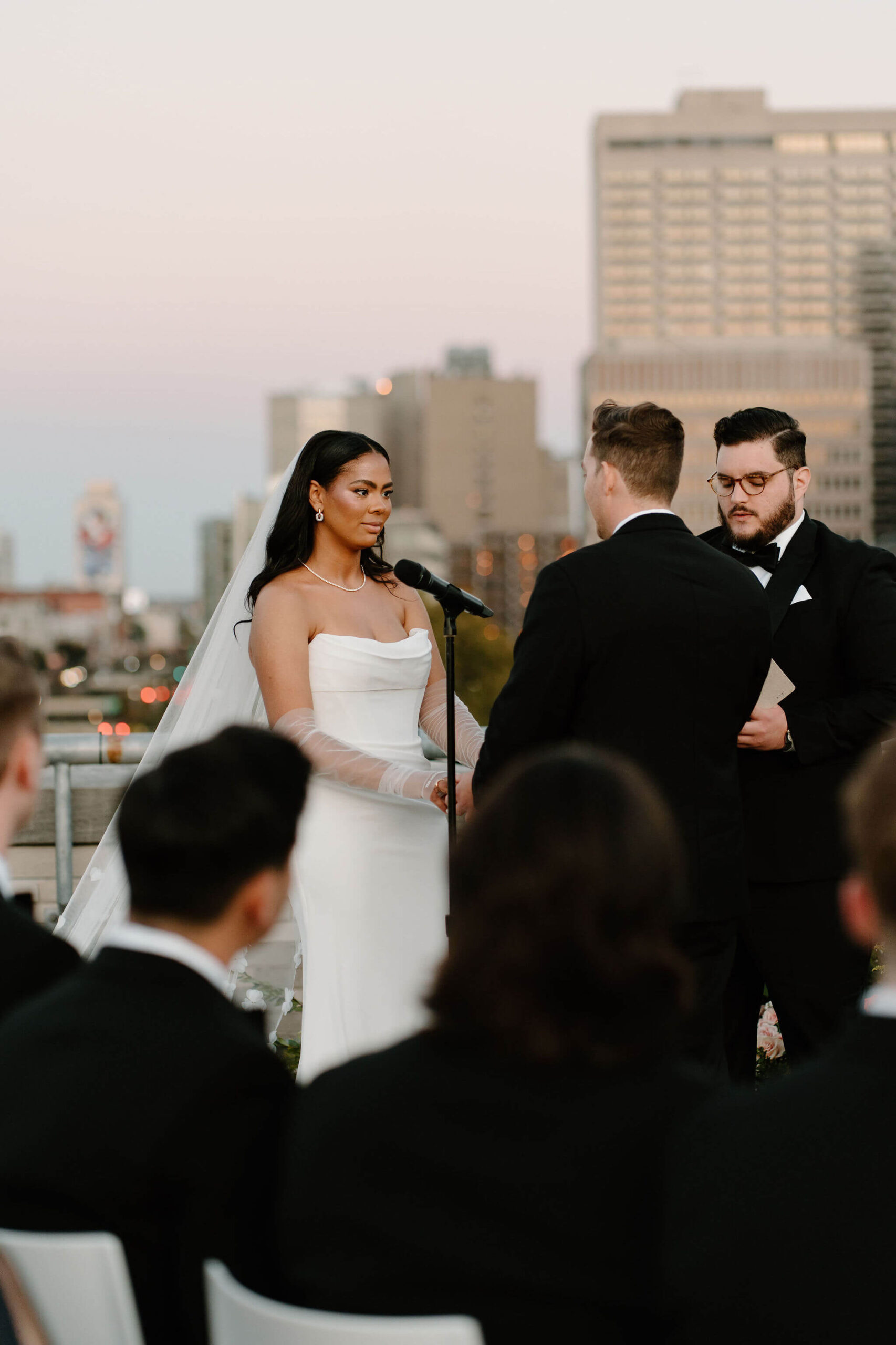bride holding groom's hands and looking at him softly during their rooftop wedding ceremony in Philadelphia