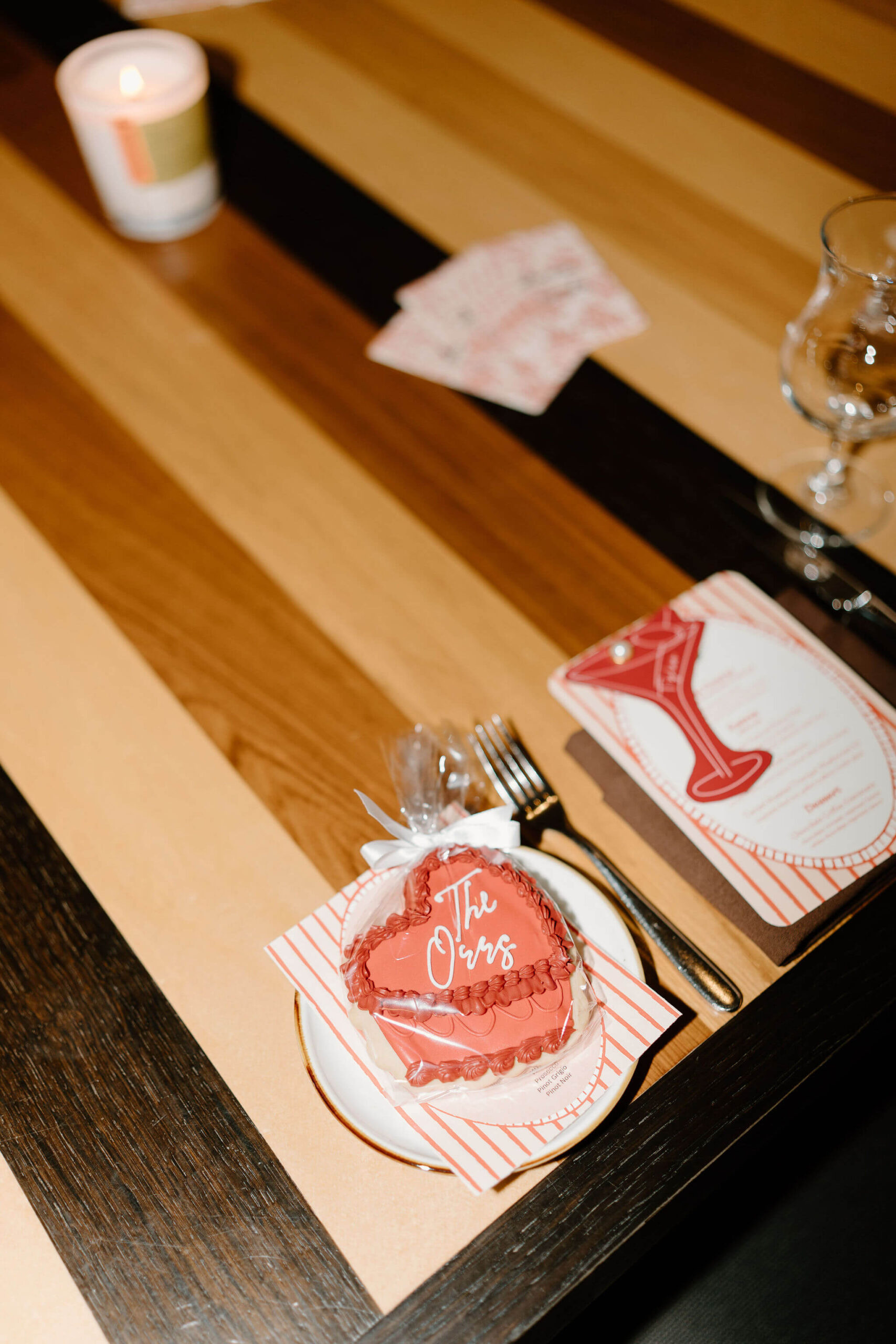 heart shaped cookie decorated in a vintage style, reading "the Orrs" in white script, as part of a decoration for a rehearsal dinner on a wooden table