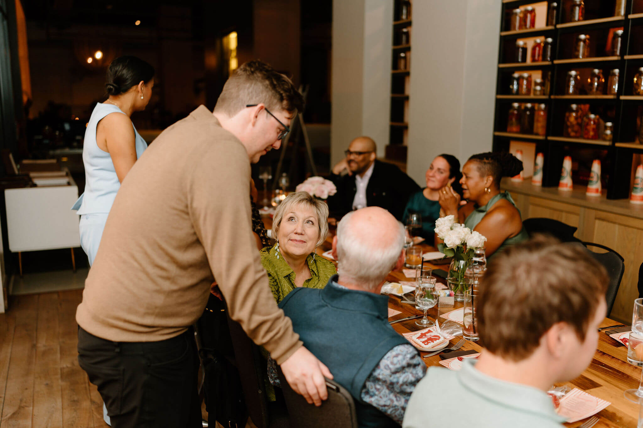 groom leaning over his seated parents to talk, all smiling