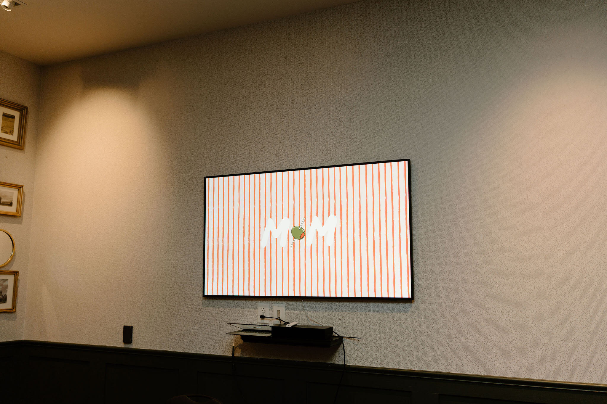 A TV screen displaying a red & white striped graphic with M&M in the middle (For the bride & groom's initials)