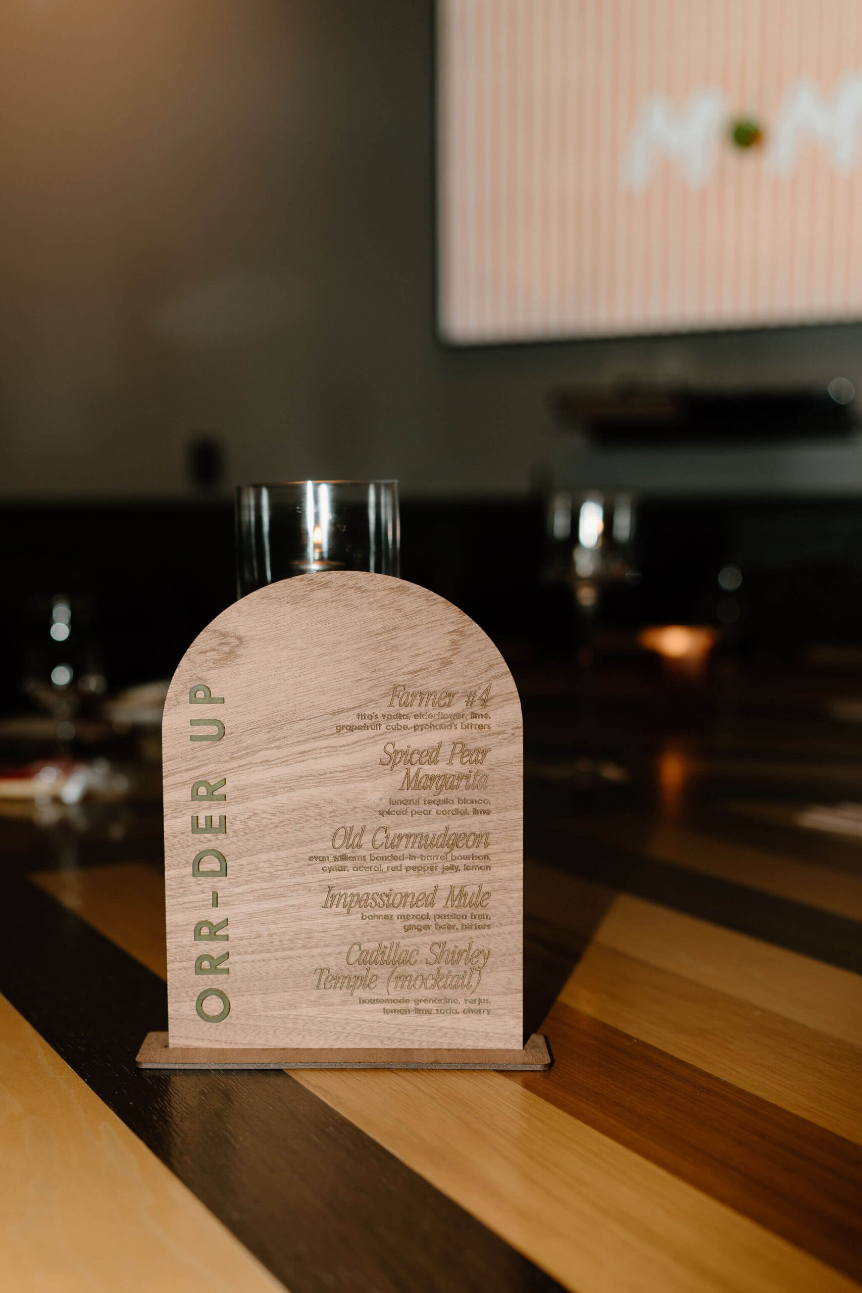 rounded half-moon wooden drink menu with gold lettering