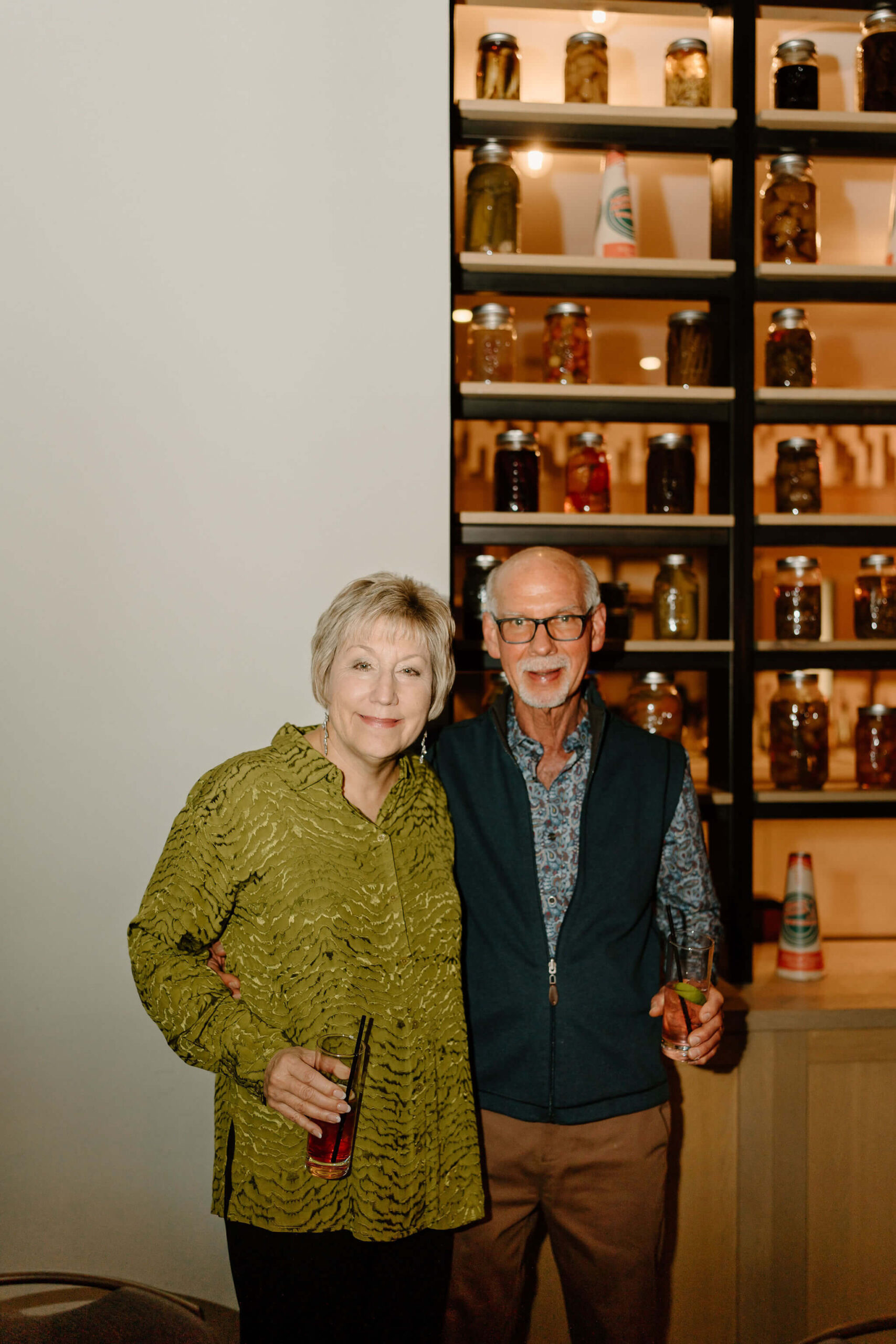 parents of the groom holding beverages and smiling at the camera