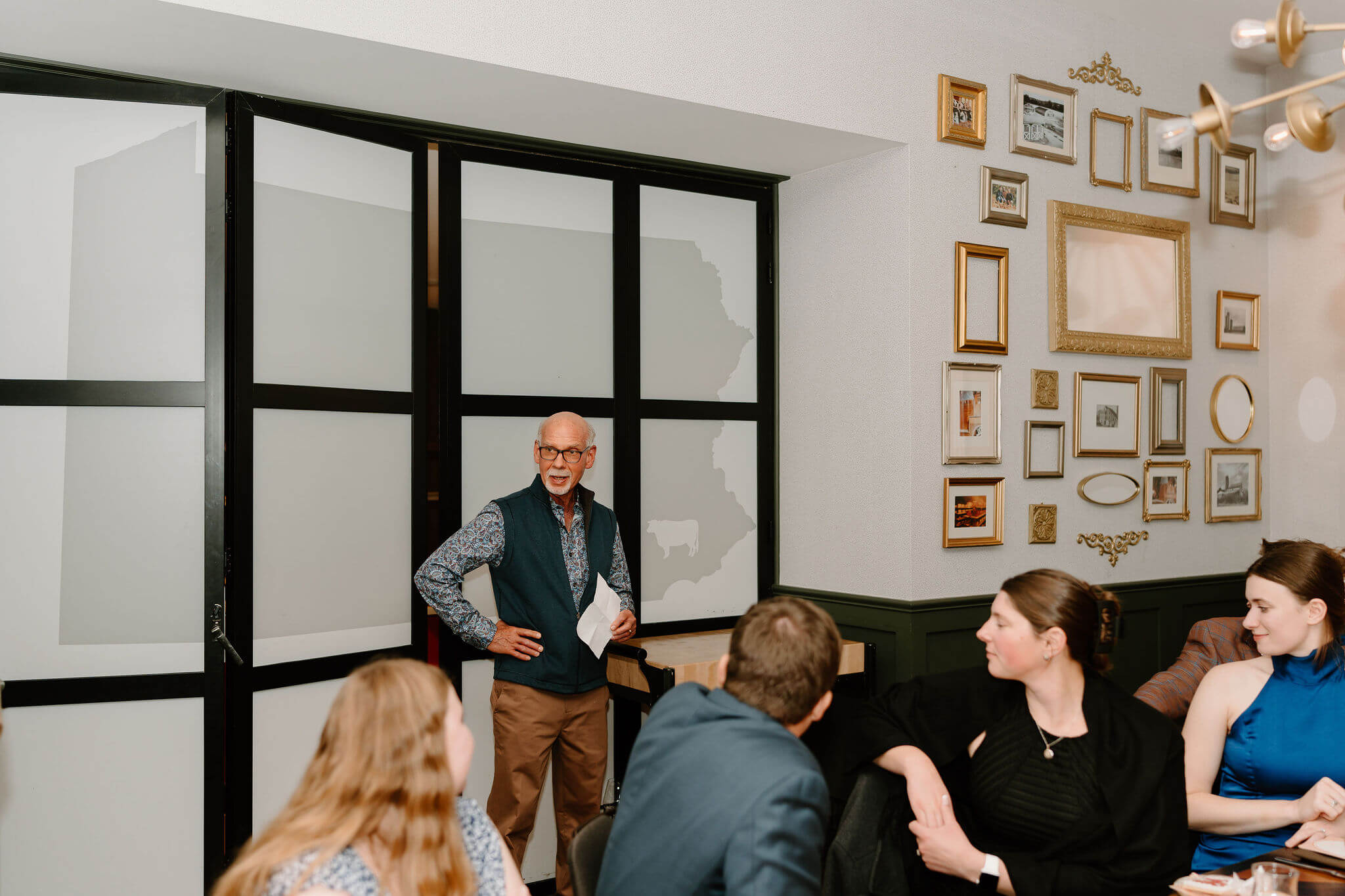 father of the groom giving a speech to seated guests at the rehearsal dinner