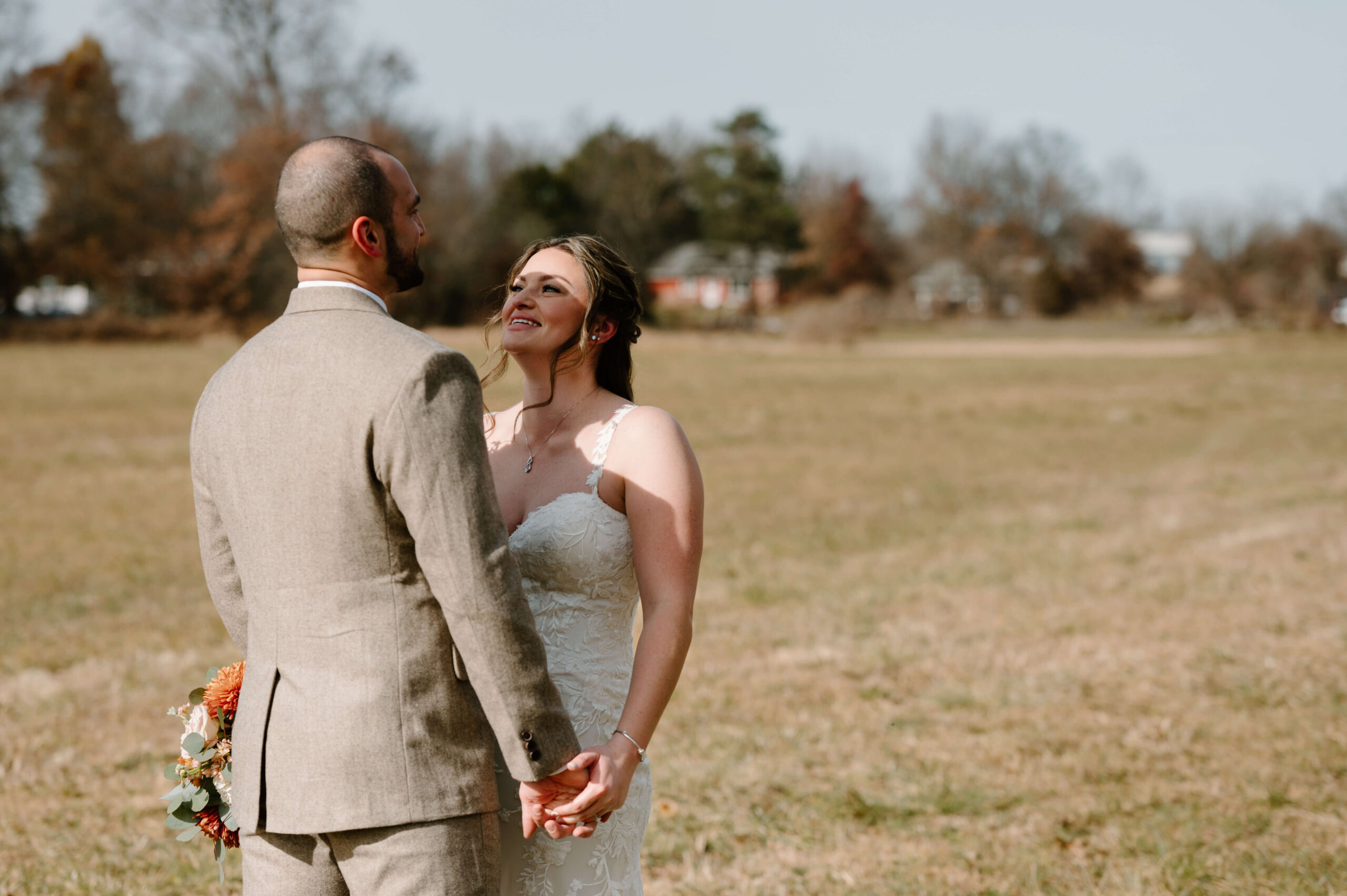 bride and groom holding hands and smiling at each other during their first look on their wedding day