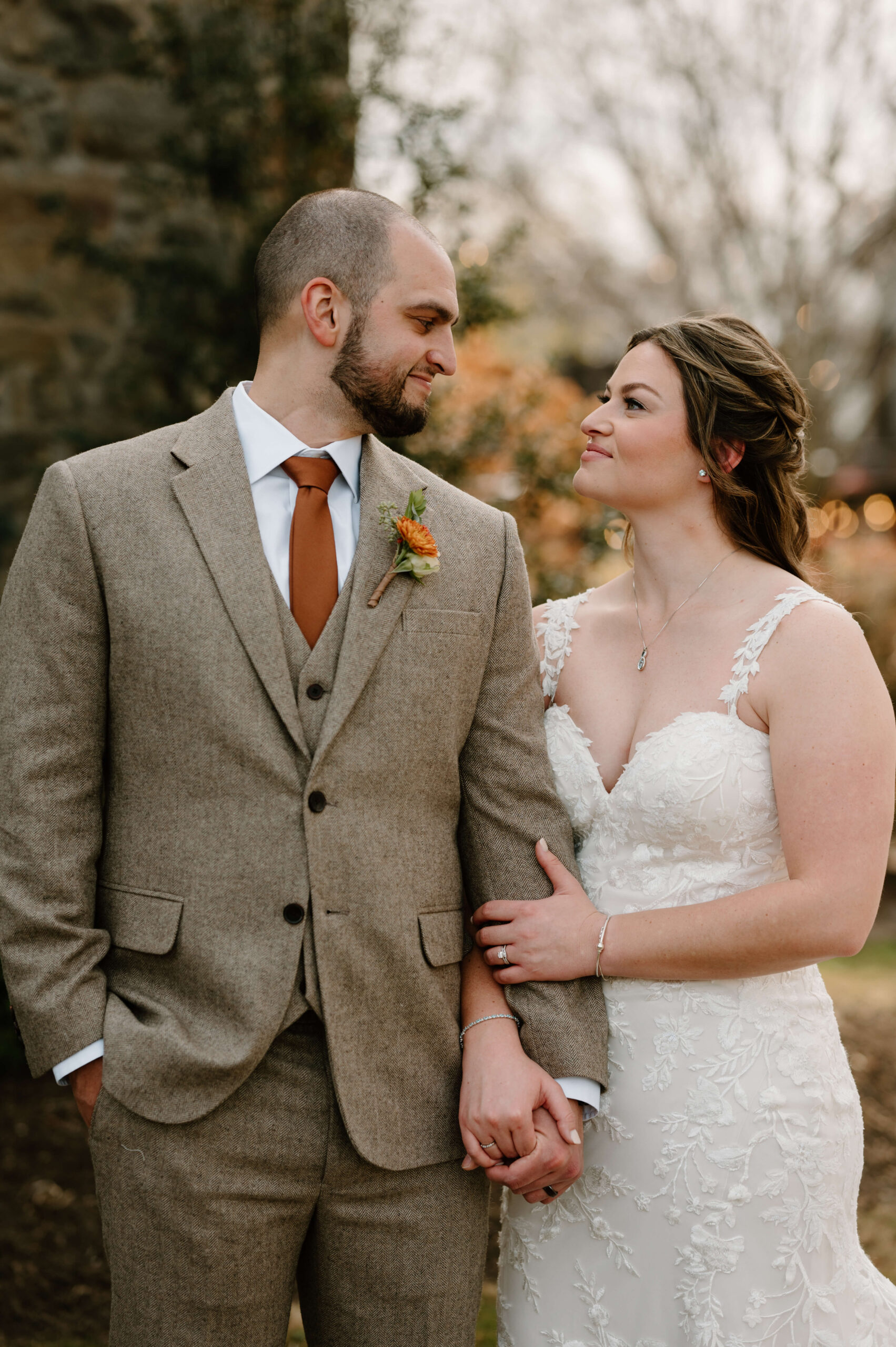 bride and groom holding hands and smiling softly at each other on their November wedding day at the Farm