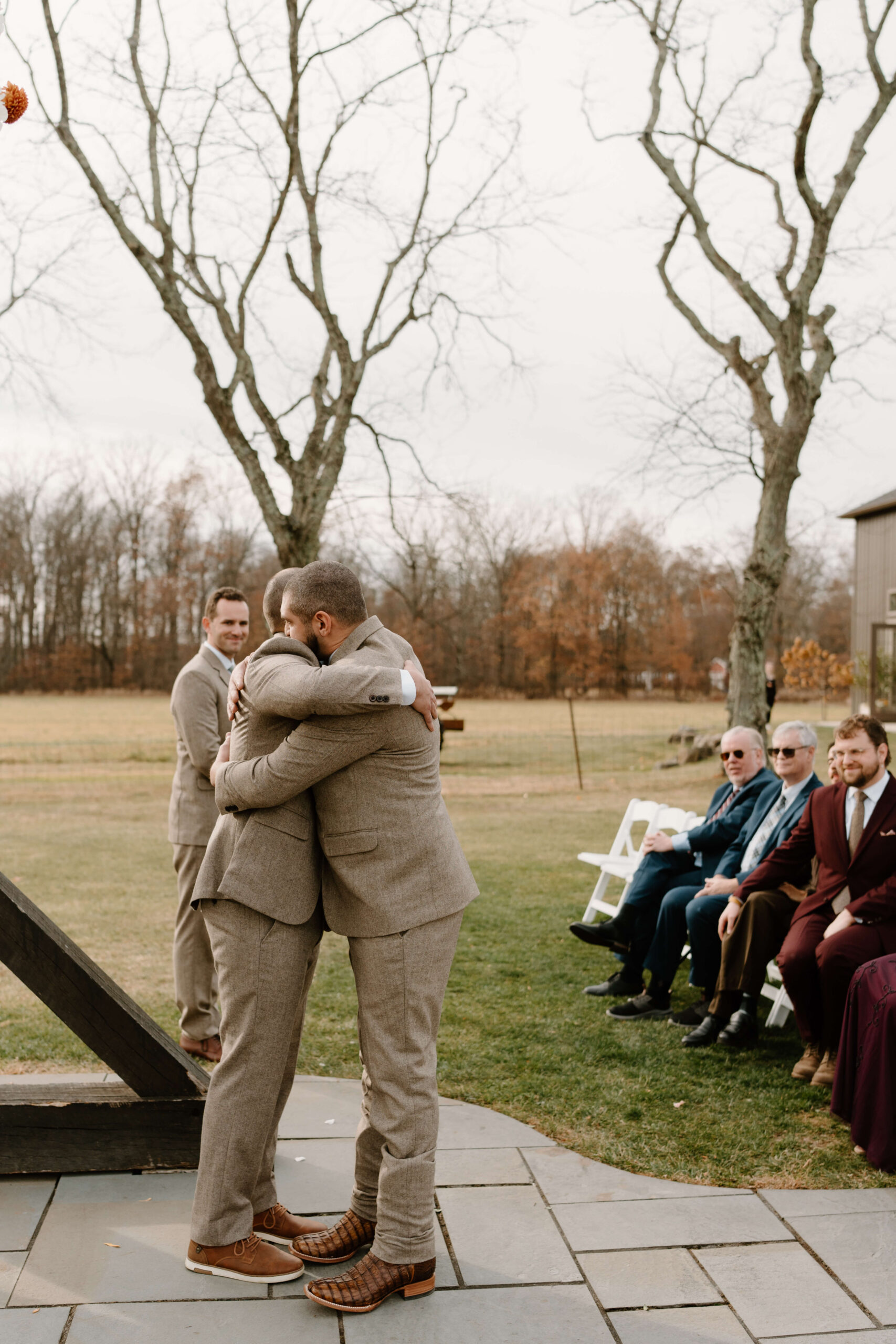 groom and his brother embracing at the end of the aisle during a wedding ceremony