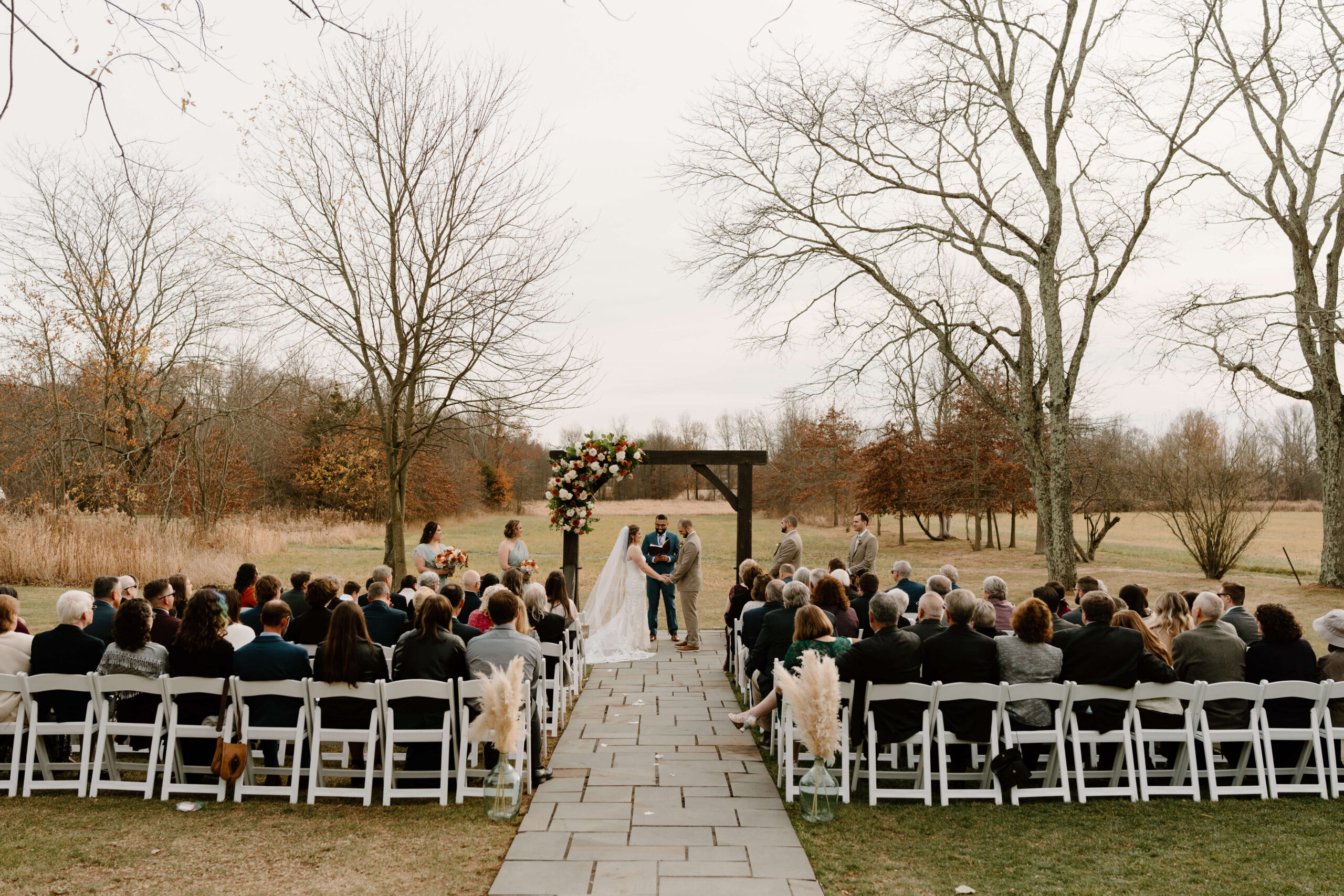 wide image of bride and groom holding hands during their November wedding ceremony in Quakertown, PA