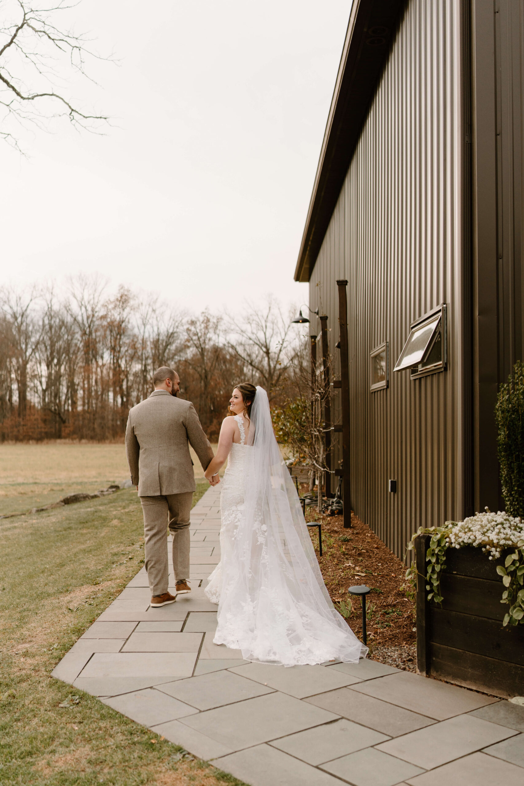 bride looking over her shoulder and smiling widely as she and her groom depart their wedding ceremony