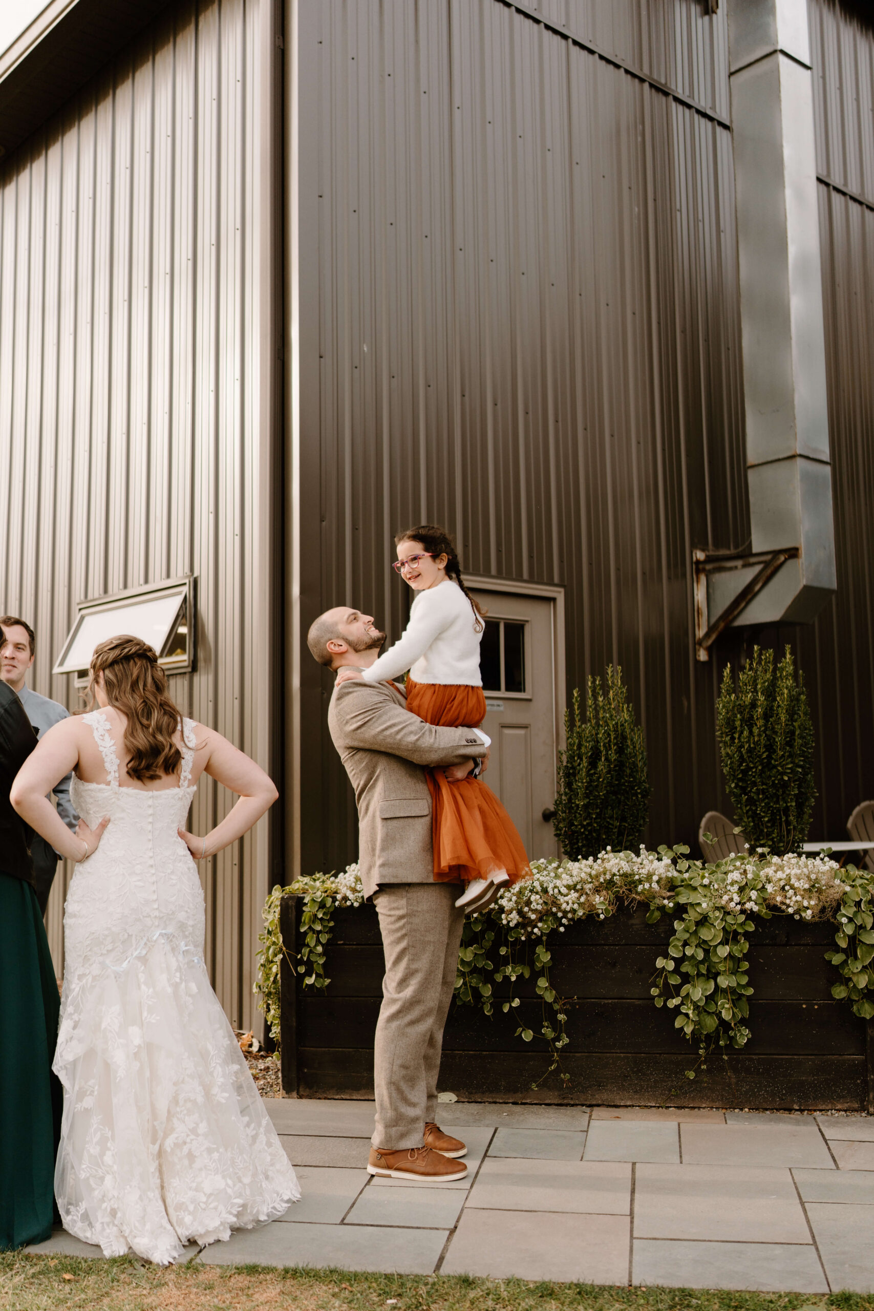 groom lifting up his niece in an orange tulle dress, both smiling widely
