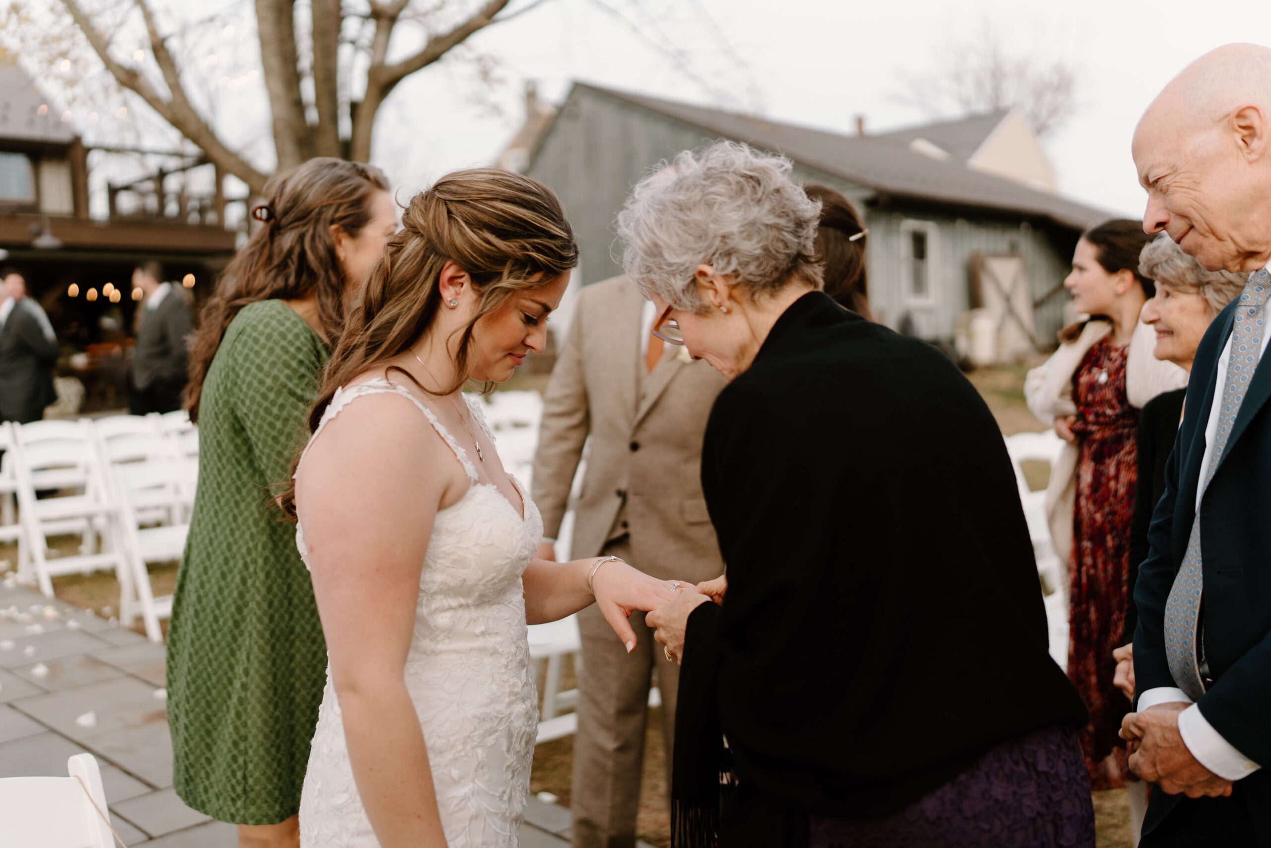 extended family gathering around bride to admire her engagement ring and wedding band during cocktail hour