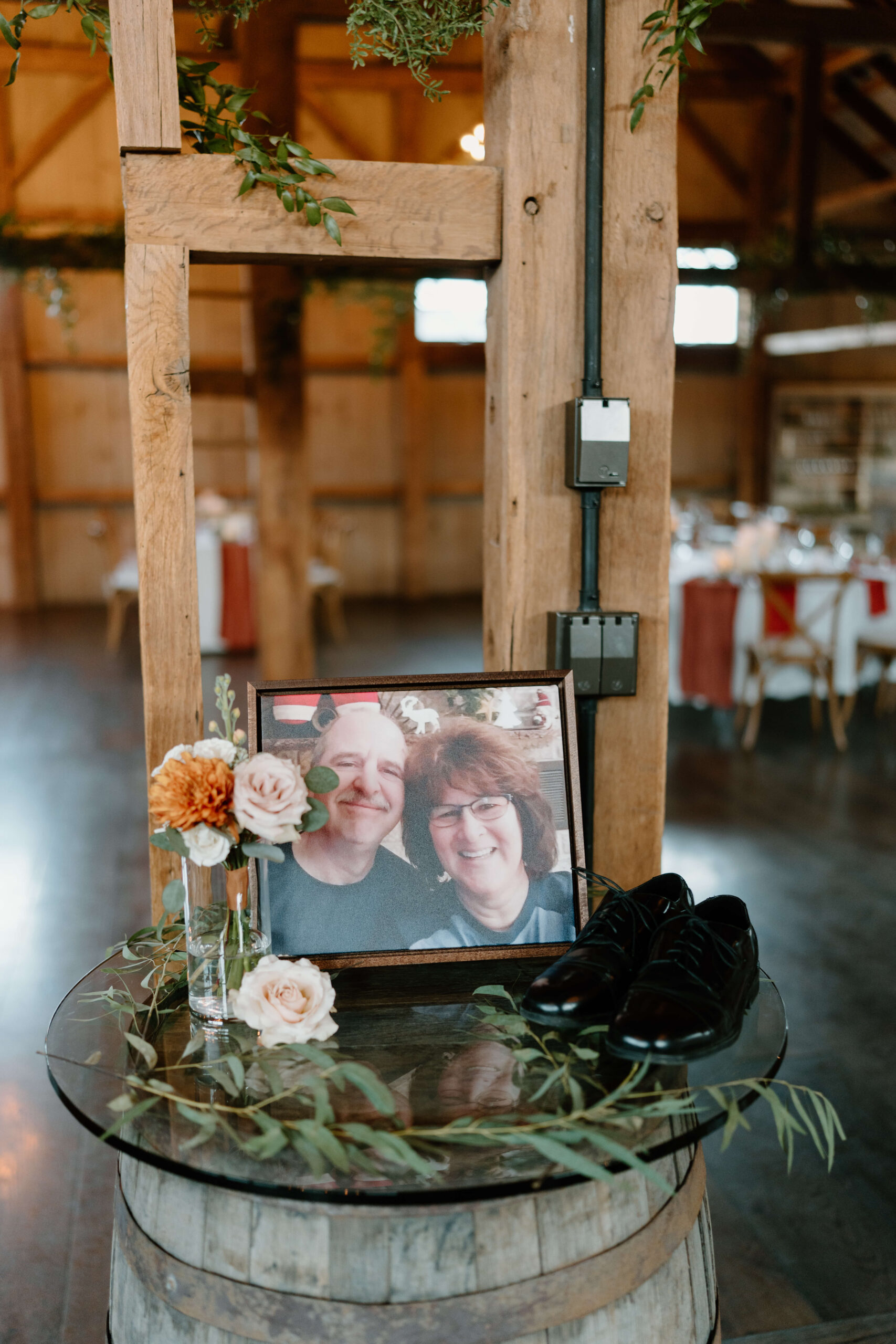 memorial table featuring a framed image of groom's late parents, as well as groom's fathers' dress shoes