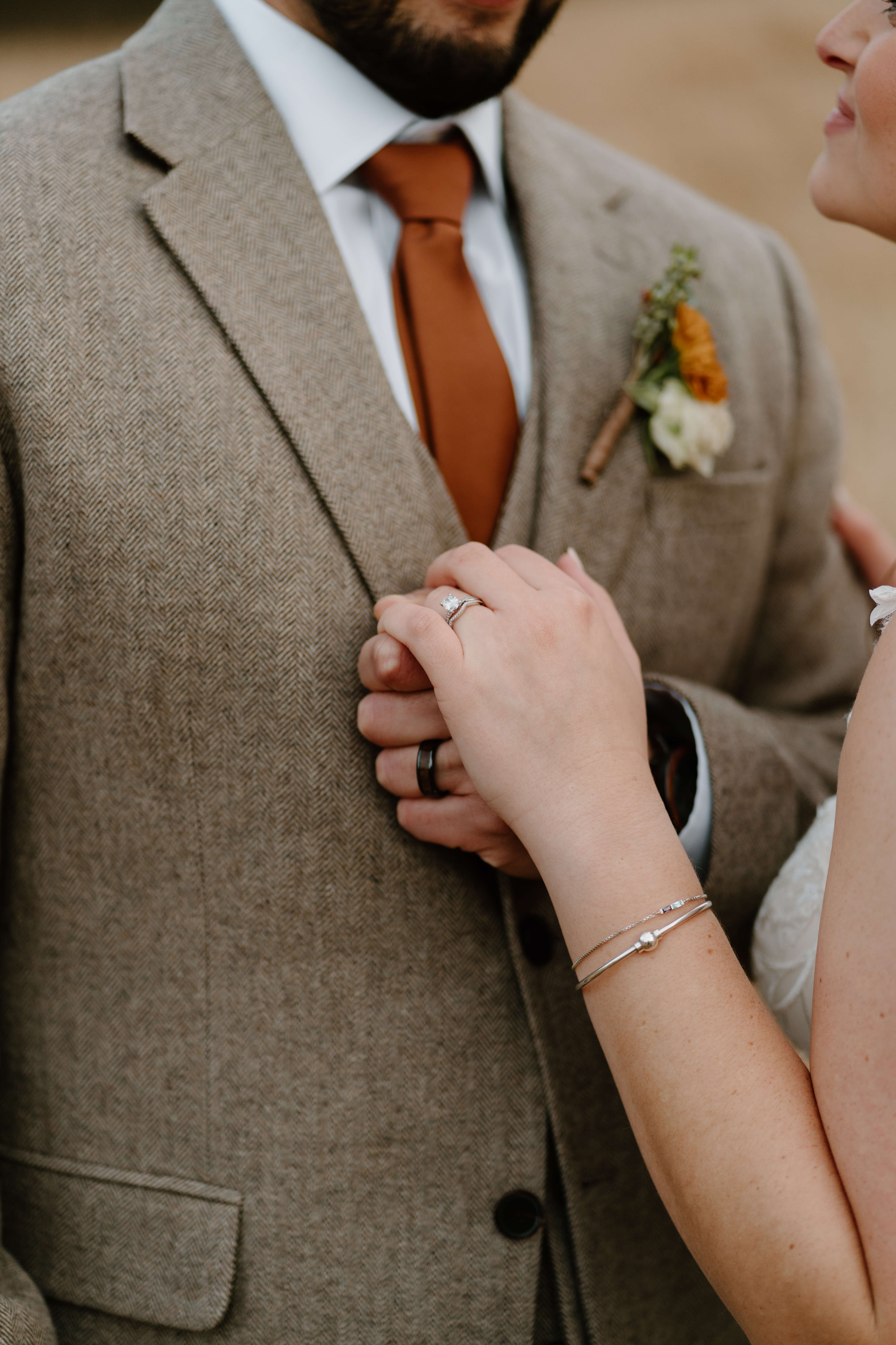 close up of bride and groom holding hands, focusing on their new wedding bands and her engagement ring