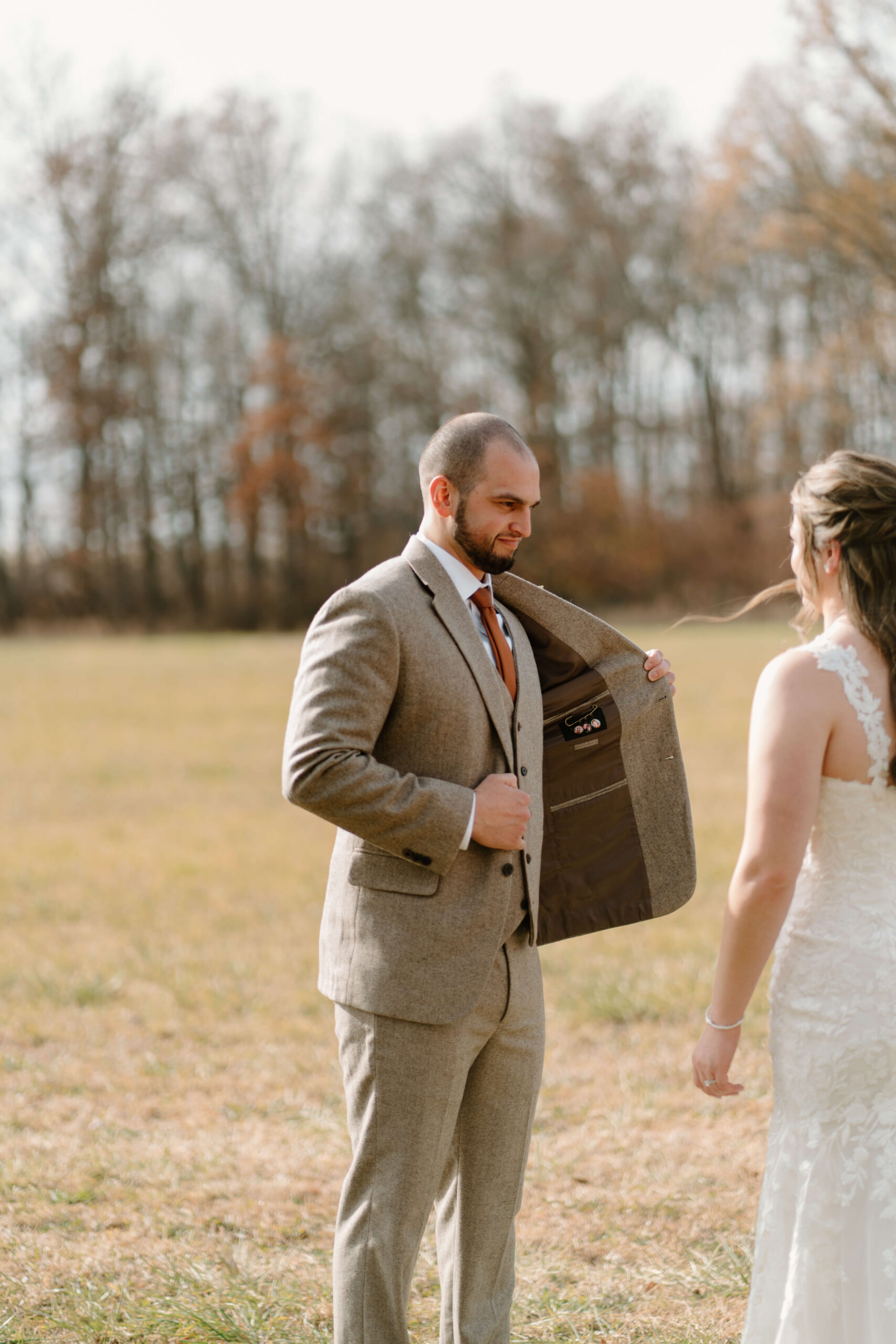 groom opening his suitjacket to show bride custom pin with photos of his late parents