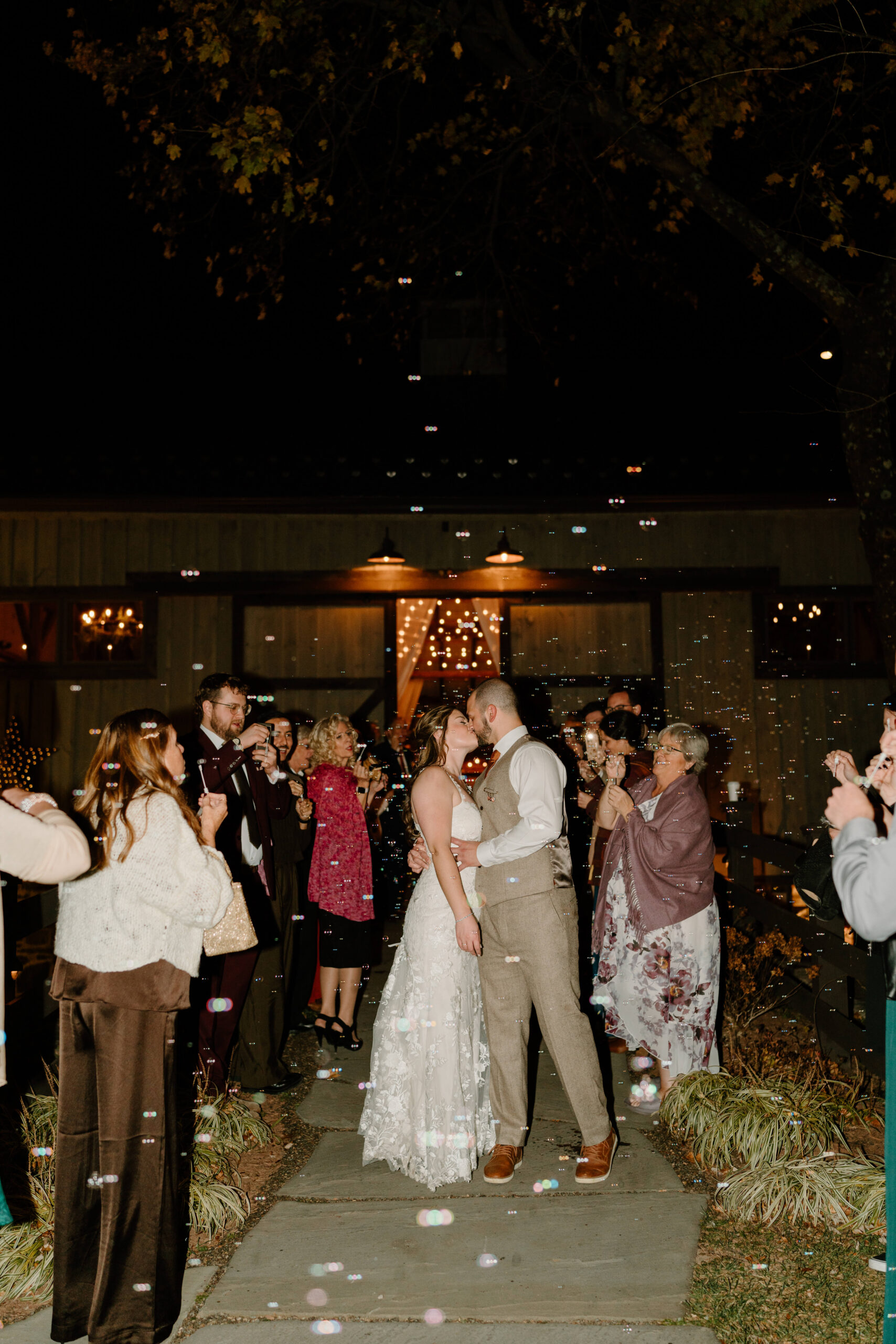 bride and groom kissing during a bubble send off after their wedding at the Farm bakery and Events