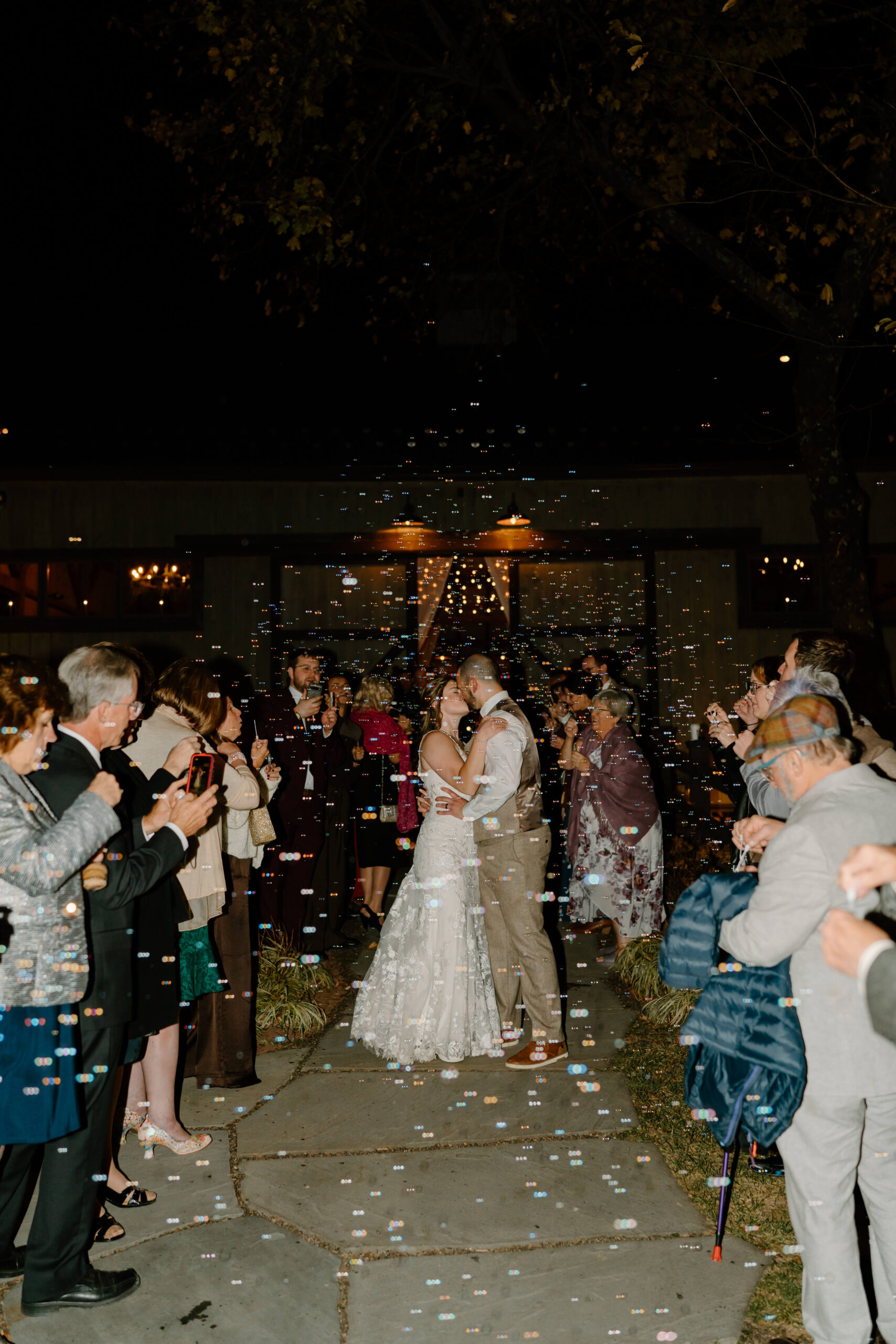 bride and groom kissing during a bubble send off after their wedding at the Farm bakery and Events