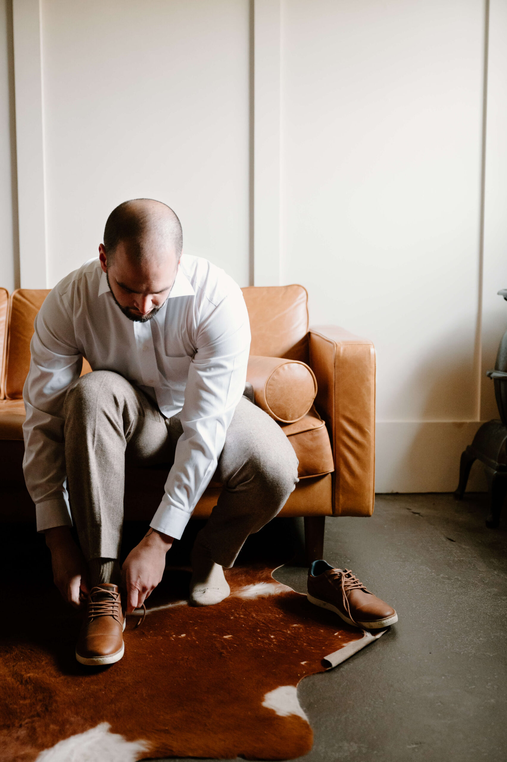 groom seated, tying his dress shoes