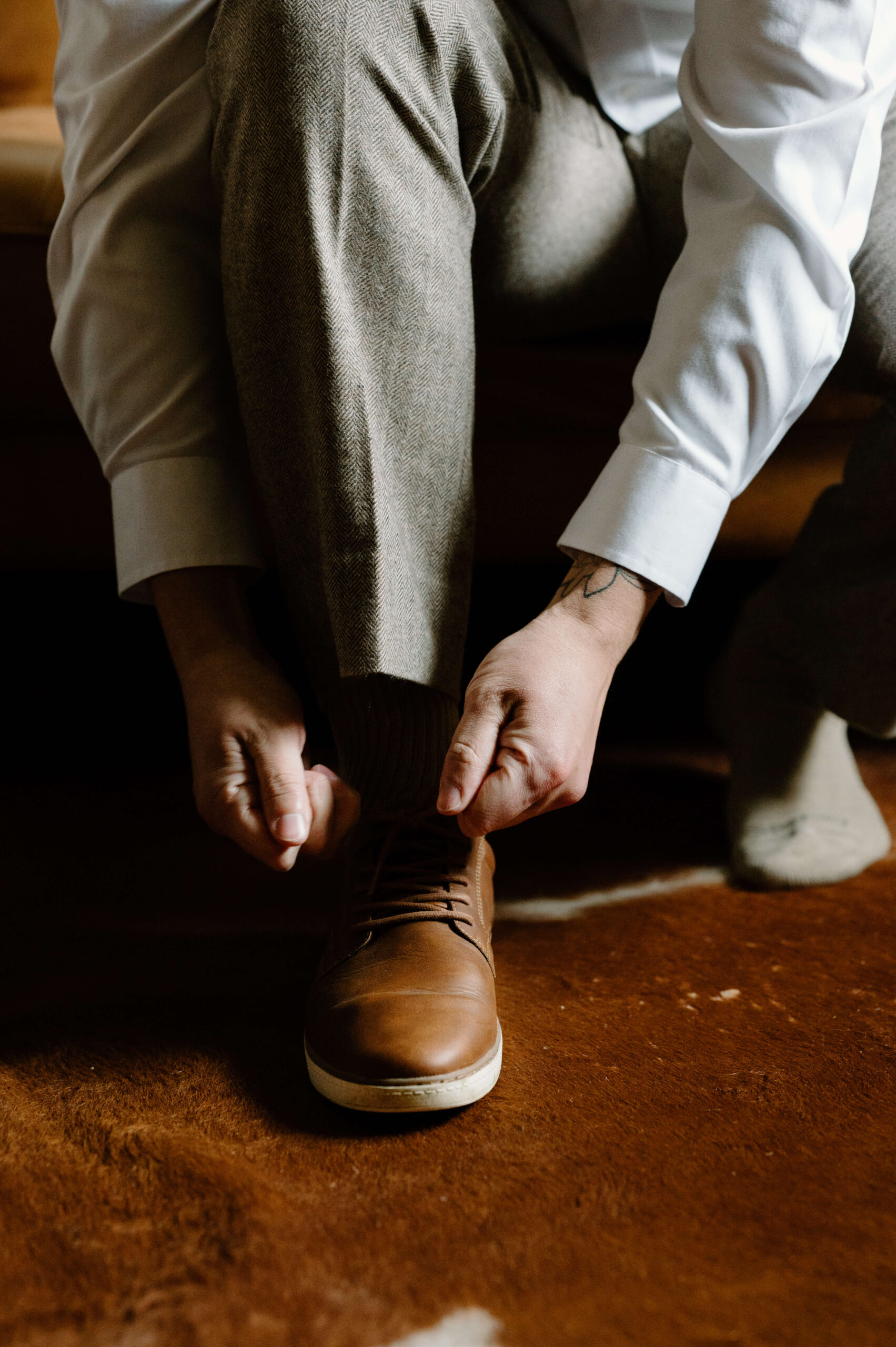 close up of groom's hands tying his dress shoes