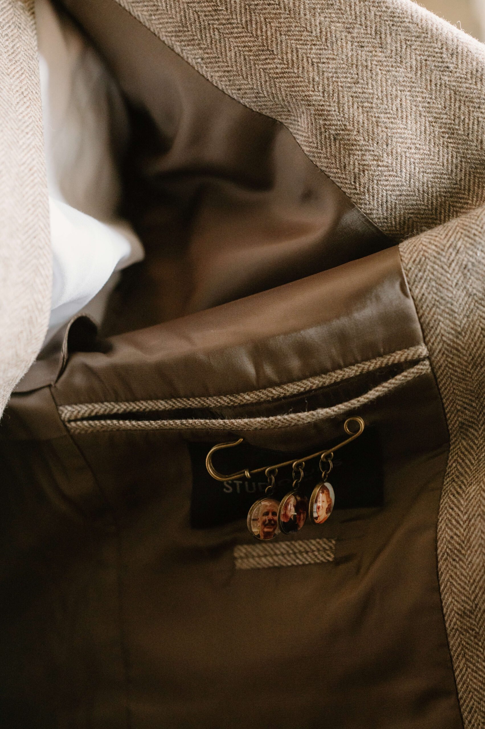 close up of a pin inside the groom's jacket, featuring images of his parents