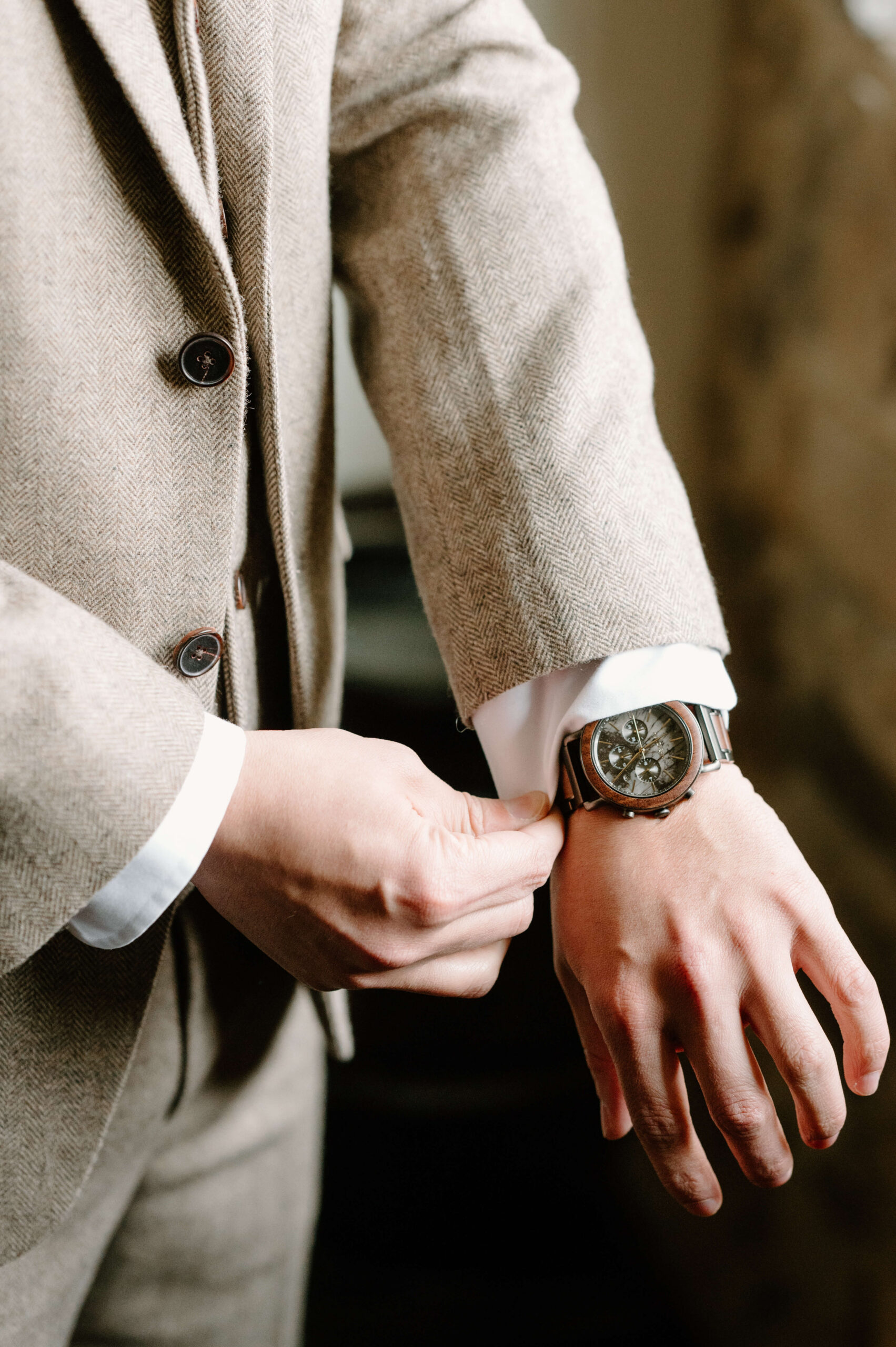close up of groom's hands as he pulls the cuffs of his dress shirt over his watch